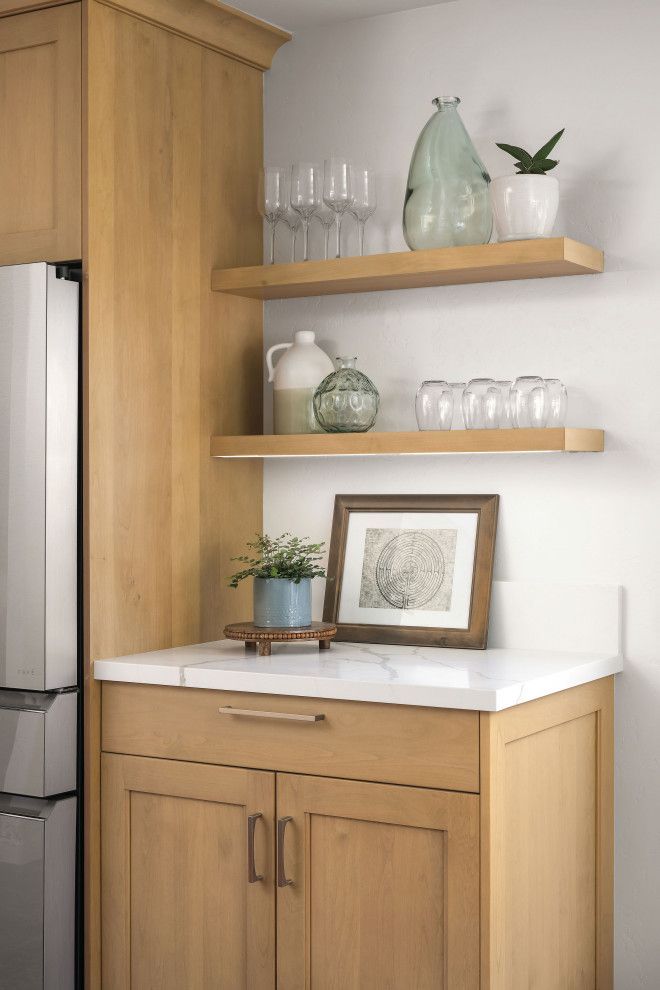 Kitchen nook with wood shelves, glass decor, framed art, and a small counter cabinet