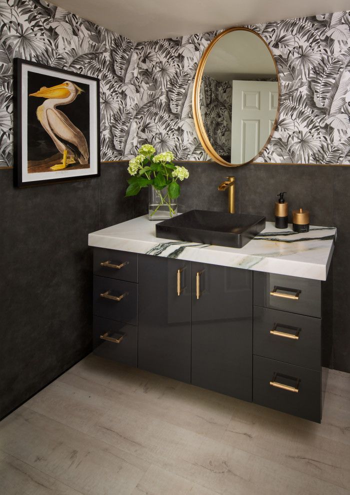 Modern bathroom vanity with black cabinets, white countertop, oval mirror, gold fixtures, and floral decor