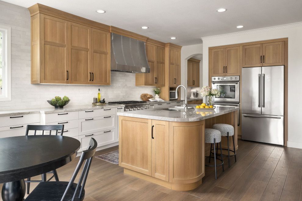 Bright modern kitchen with wood cabinets, stainless-steel appliances, island, and round dining table