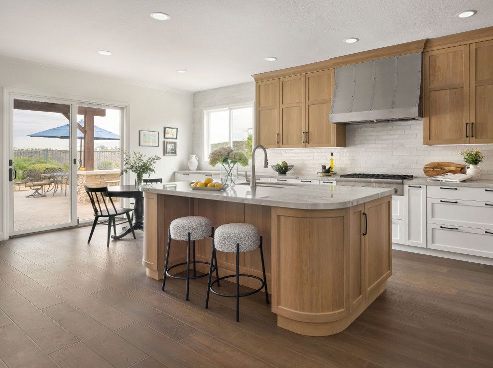 Bright modern kitchen with wood cabinets, island seating, and a dining area by patio doors