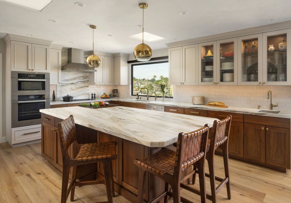 Modern kitchen with large marble island, wood cabinetry, and brass pendant lights