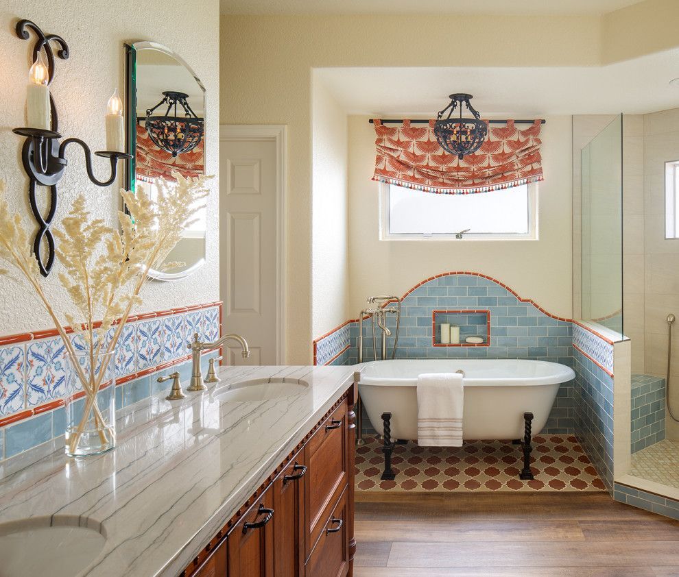 Bright bathroom with a freestanding tub, marble vanity, blue tile accents, and a window seat