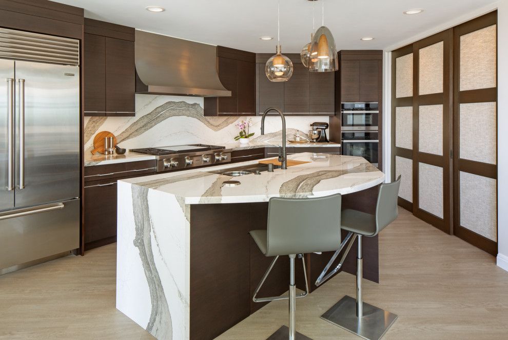 Modern kitchen with marble island, pendant lights, stainless fridge, and built-in shelving