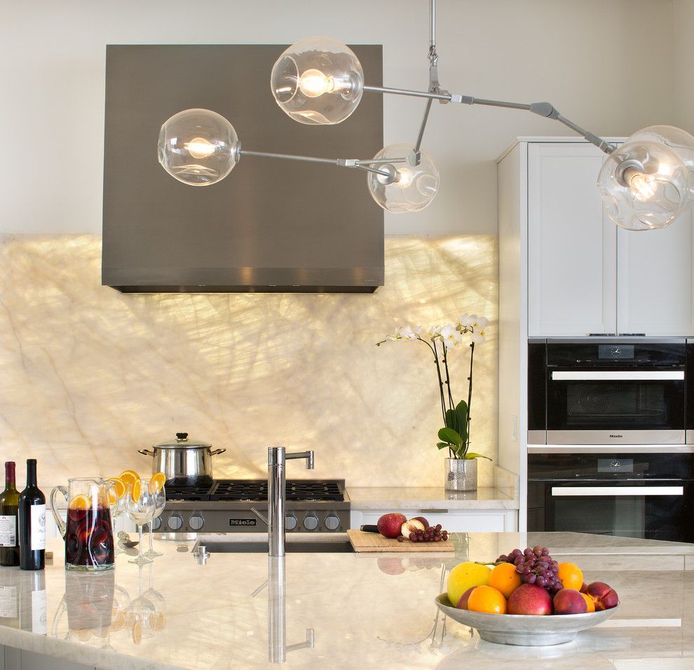 Modern kitchen with island, fruit bowl, stove, sink, and pendant globe lights