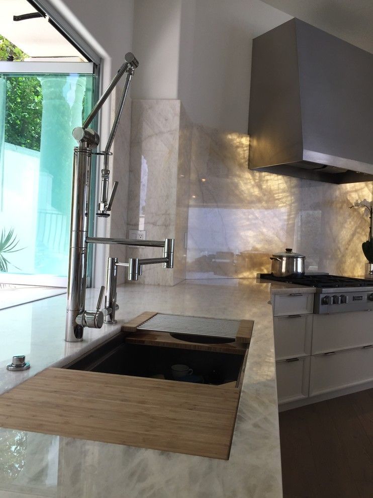 Modern kitchen sink beside a window, with a gooseneck faucet and stove in the background