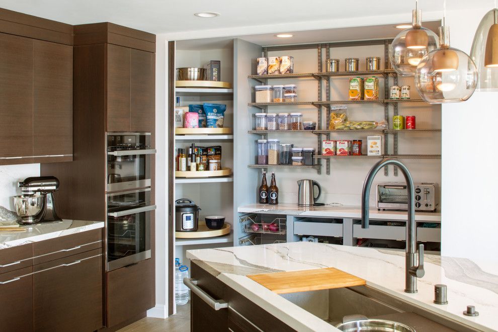Modern kitchen with open pantry shelves, dark wood cabinets, white island, and stainless-steel appliances