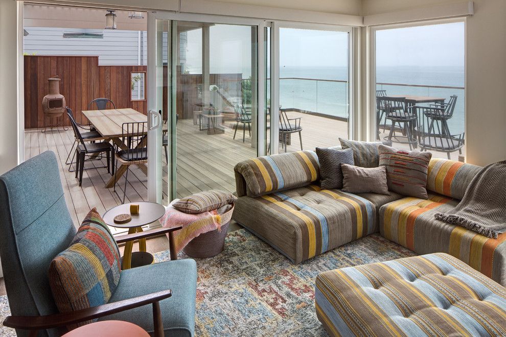 Bright living room with striped sofas and chairs overlooking a balcony and ocean view