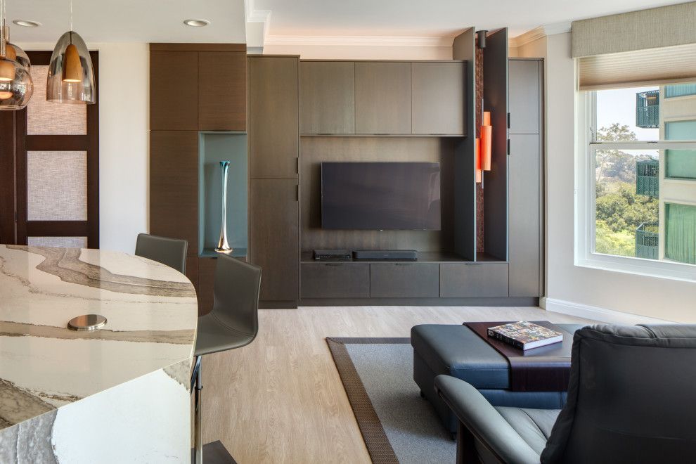 Modern living room with large TV wall, sectional sofa, marble counter, and city view window