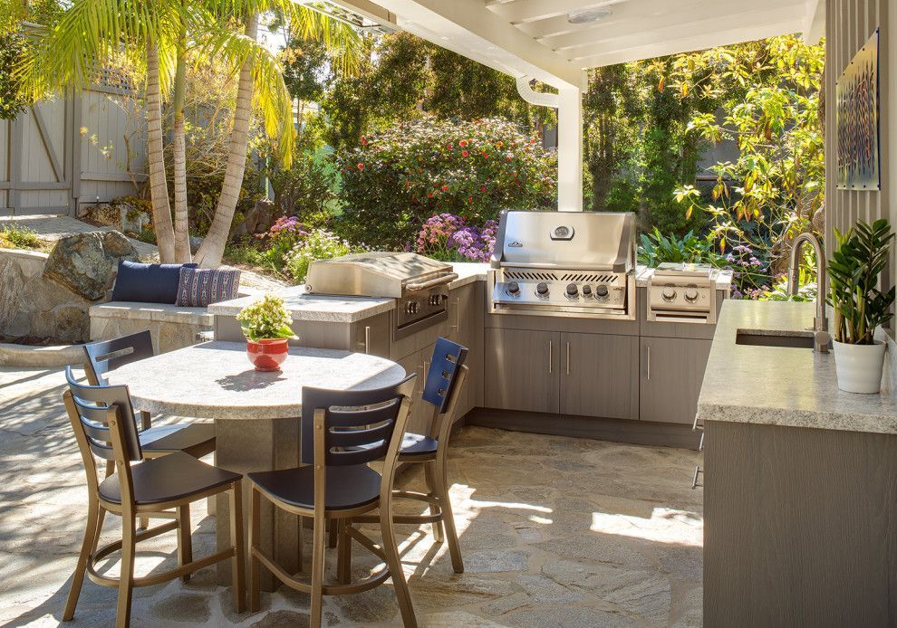 Outdoor patio with dining table, cushioned seating, and a stainless steel grill under a covered pergola