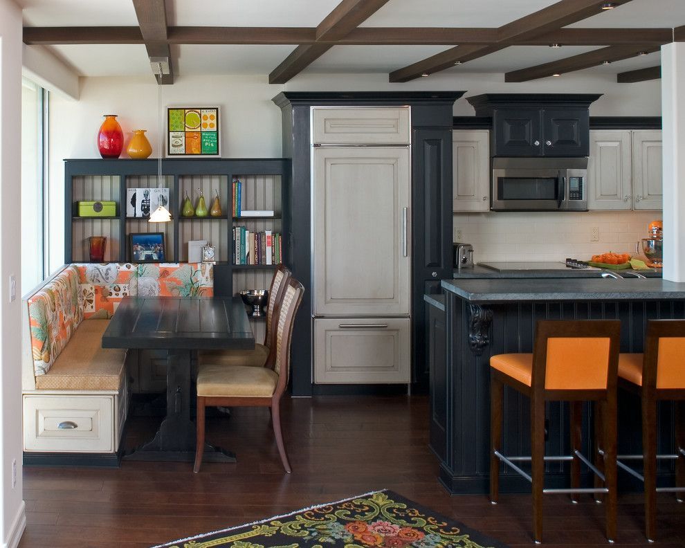 Cozy kitchen with dark cabinets, white island, breakfast nook, and wood-beam ceiling