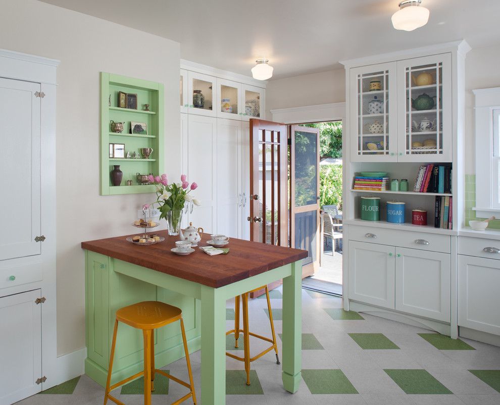 Bright white kitchen with green accents, wooden island, and open glass door to a garden.