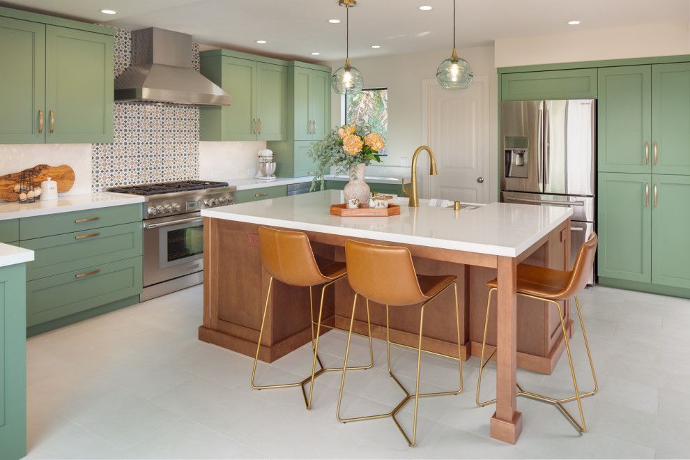 Bright modern kitchen with mint cabinets, marble island, brass stools, and stainless steel appliances