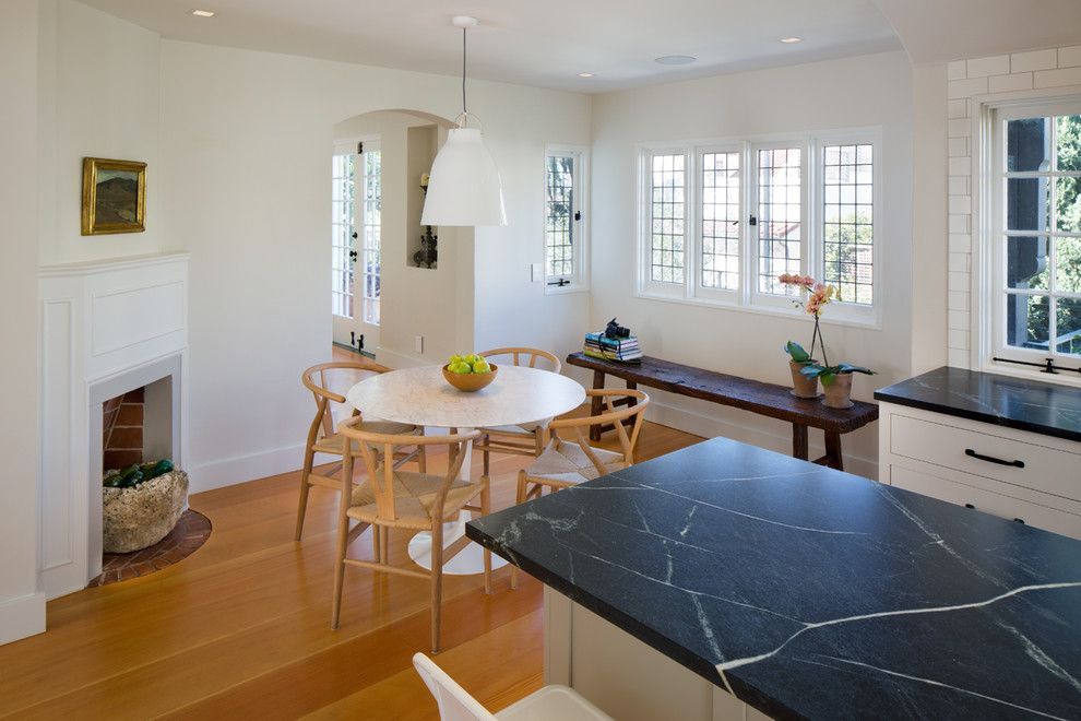 Bright kitchen and dining area with round table, white cabinets, and dark countertop