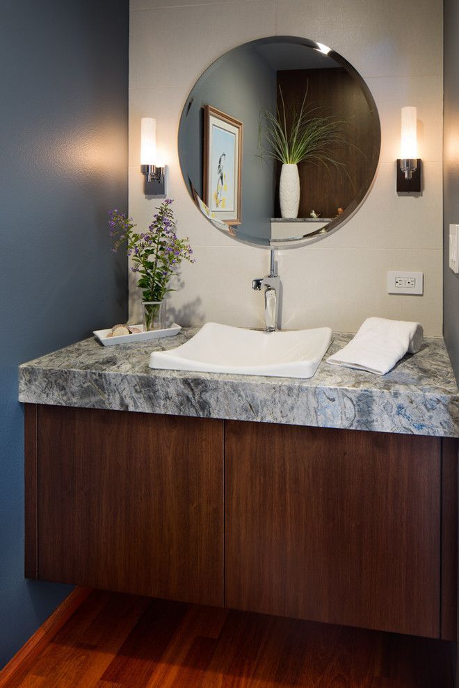 Modern bathroom vanity with granite countertop, vessel sink, round mirror, and wall sconces
