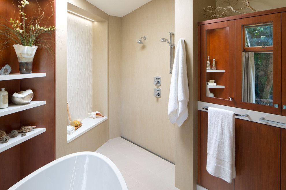 Modern bathroom with wood cabinets, bathtub, window seat, and white towels