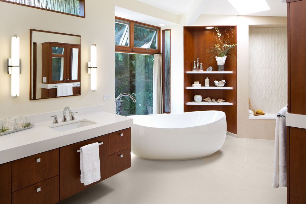 Modern bathroom with white tub, wood vanity, large mirror, and built-in shelving