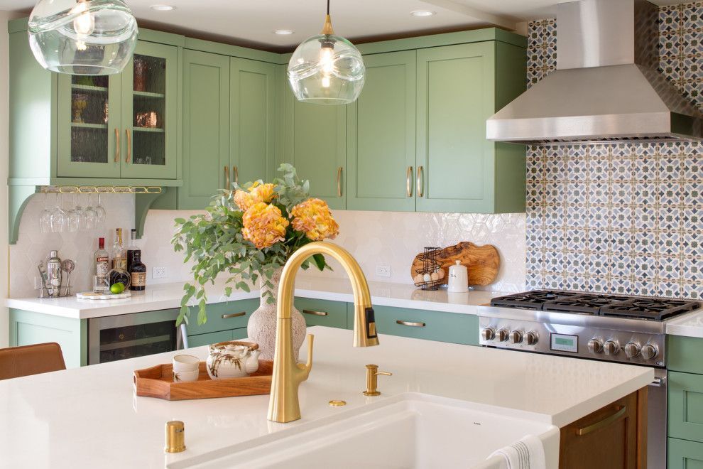 Bright mint-green kitchen with white island, gold faucet, flowers, and stainless-steel stove and hood