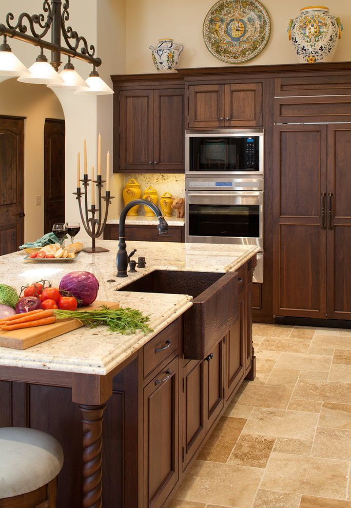 Warm kitchen with dark wood cabinets, built-in oven, granite island, and fruit and bread on the counter.