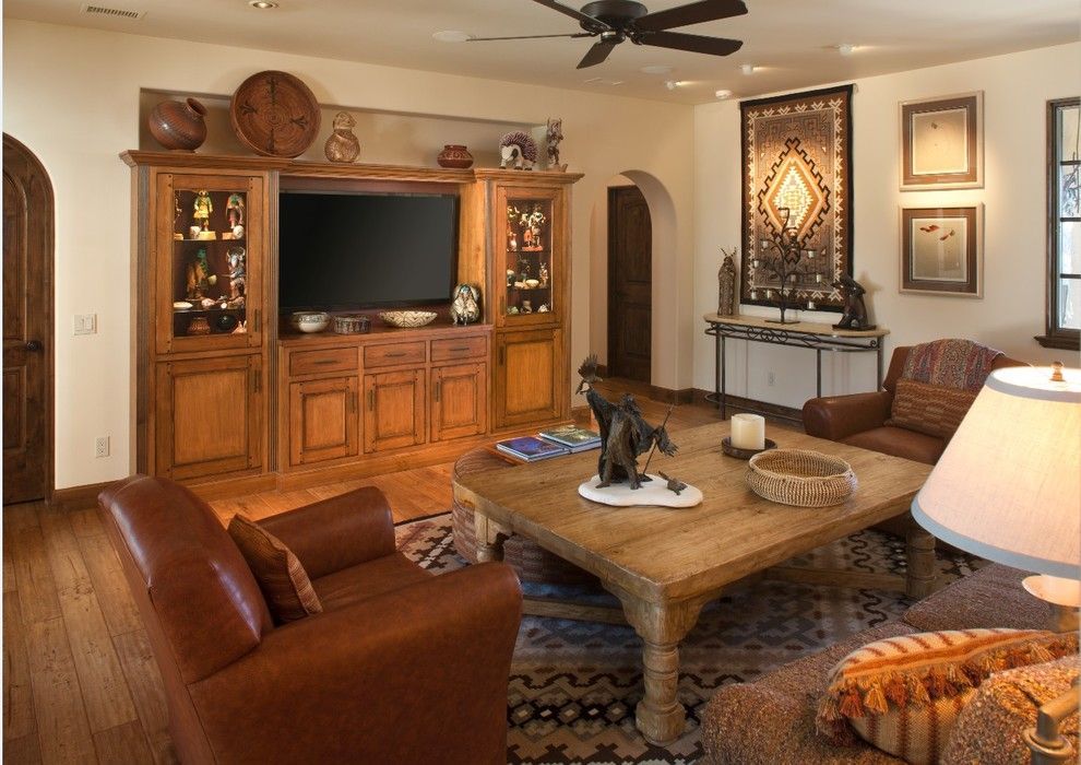 Cozy living room with wooden entertainment center, leather chairs, coffee table, lamp, and decorative fireplace display