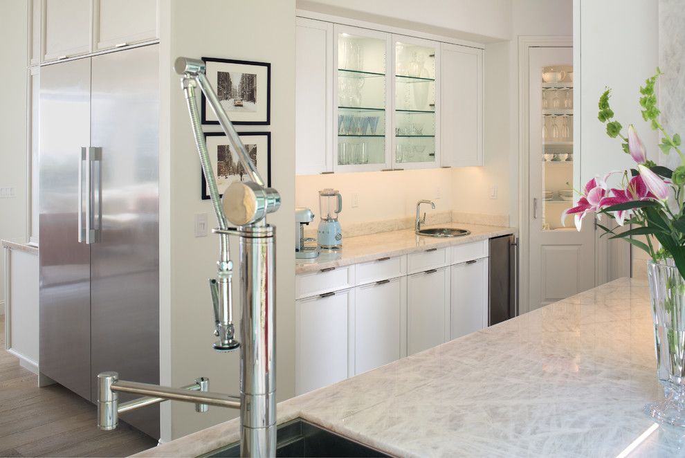 Accessible modern kitchen with stainless steel refrigerator, white cabinets, and a sink area