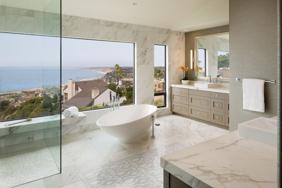 Modern bathroom with freestanding tub, marble vanity, and ocean view through large windows
