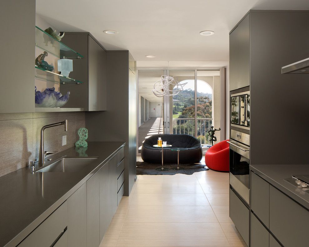 Modern kitchen opening to a bright living room with black and red chairs by a large window