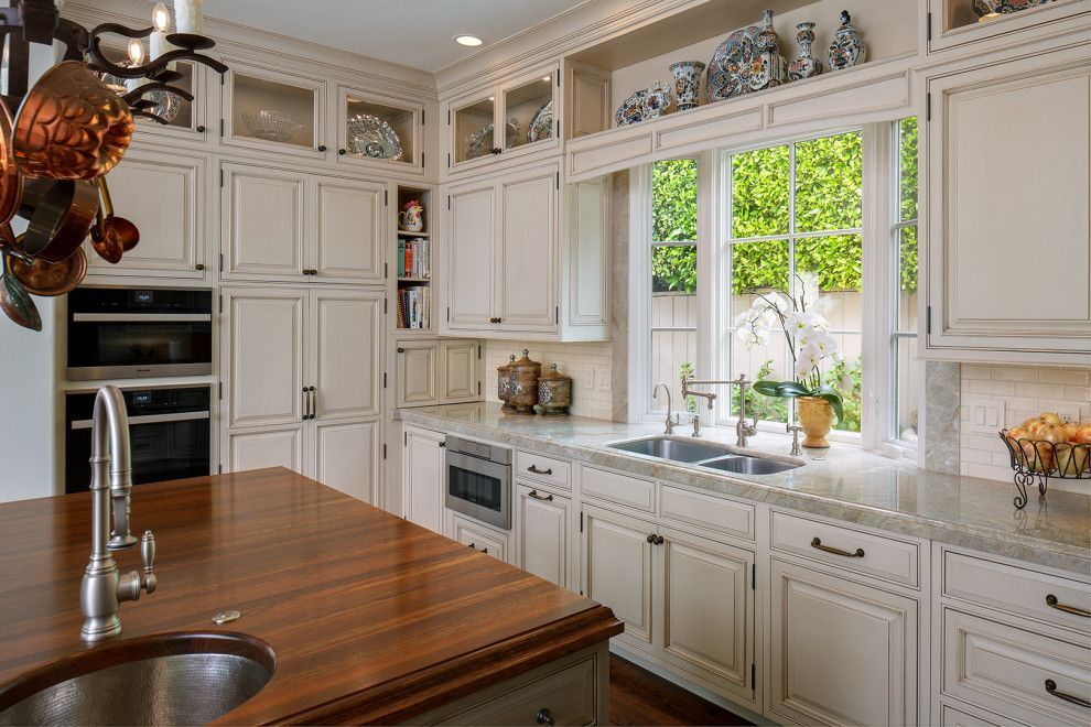 Bright white kitchen with a wooden island and large window over the sink