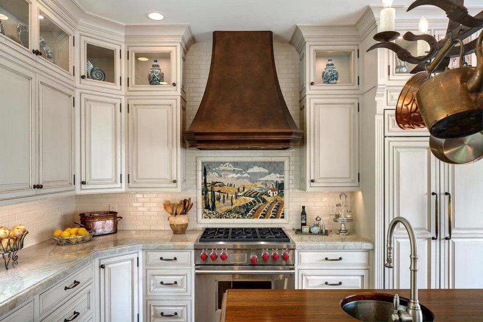 Elegant white kitchen with copper hood, built-in cabinets, and decorative tile backsplash