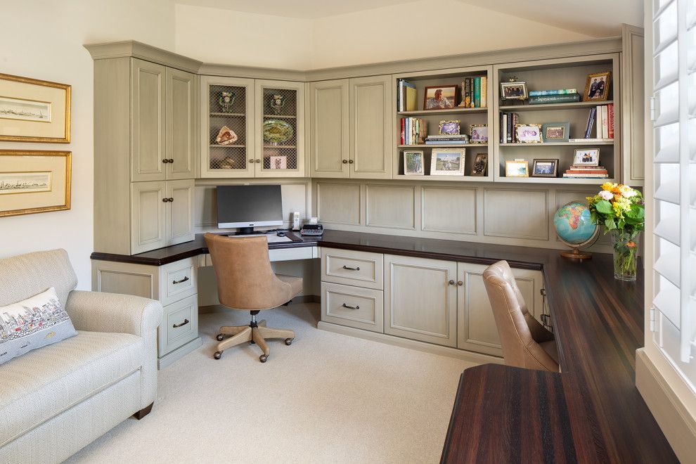 Bright home office with built-in cabinets, tan chairs, a desk, shelves, and a globe by the window.
