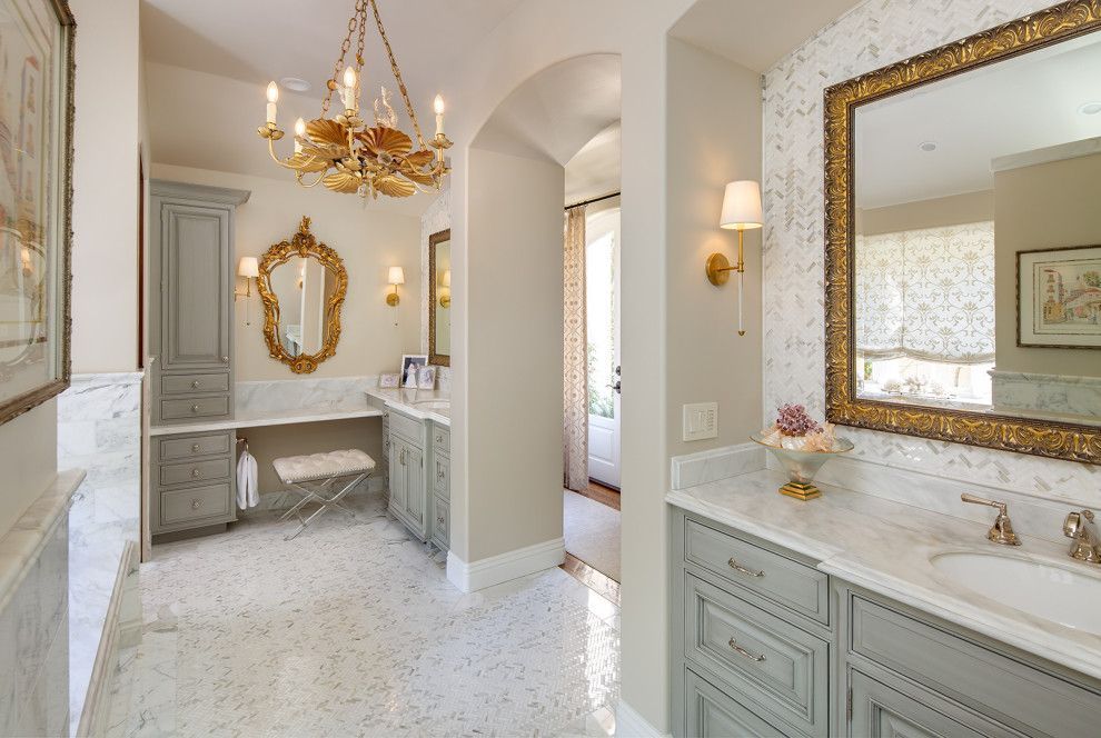 Elegant bathroom with marble vanity, gold chandelier, arched doorway, and large mirror