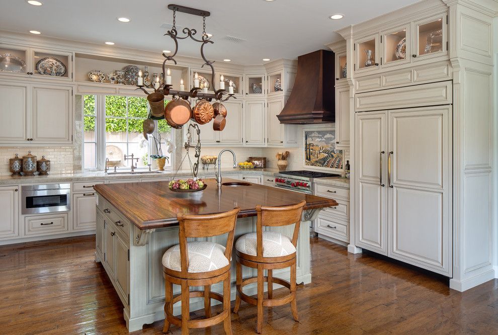 Bright white kitchen with a large wooden island, pendant light, and built-in cabinets