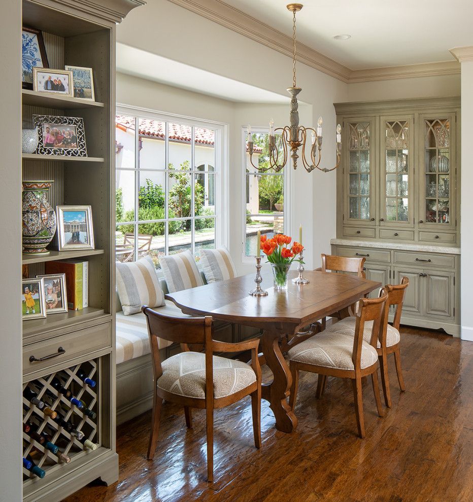 Elegant dining room with wood table, chandelier, built-in cabinets, and large windows overlooking a garden.