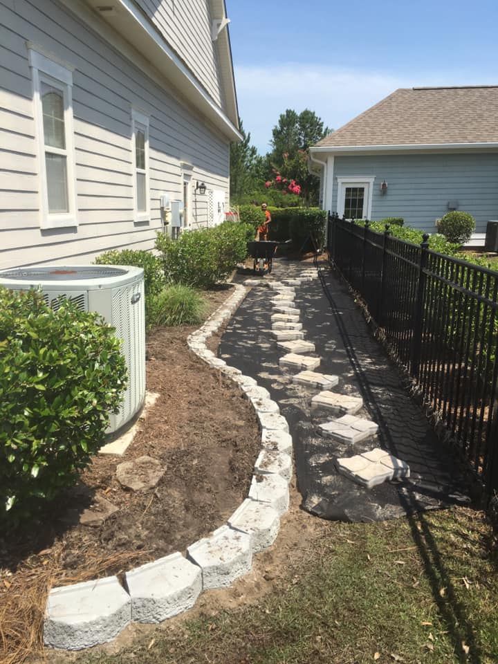 A side yard with a stepping stone path and a black fence.