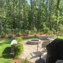 Outdoor patio with a fire pit, seating, and trees in the background.