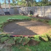 Circular area dug in a grassy yard, surrounded by turf, ready for construction.