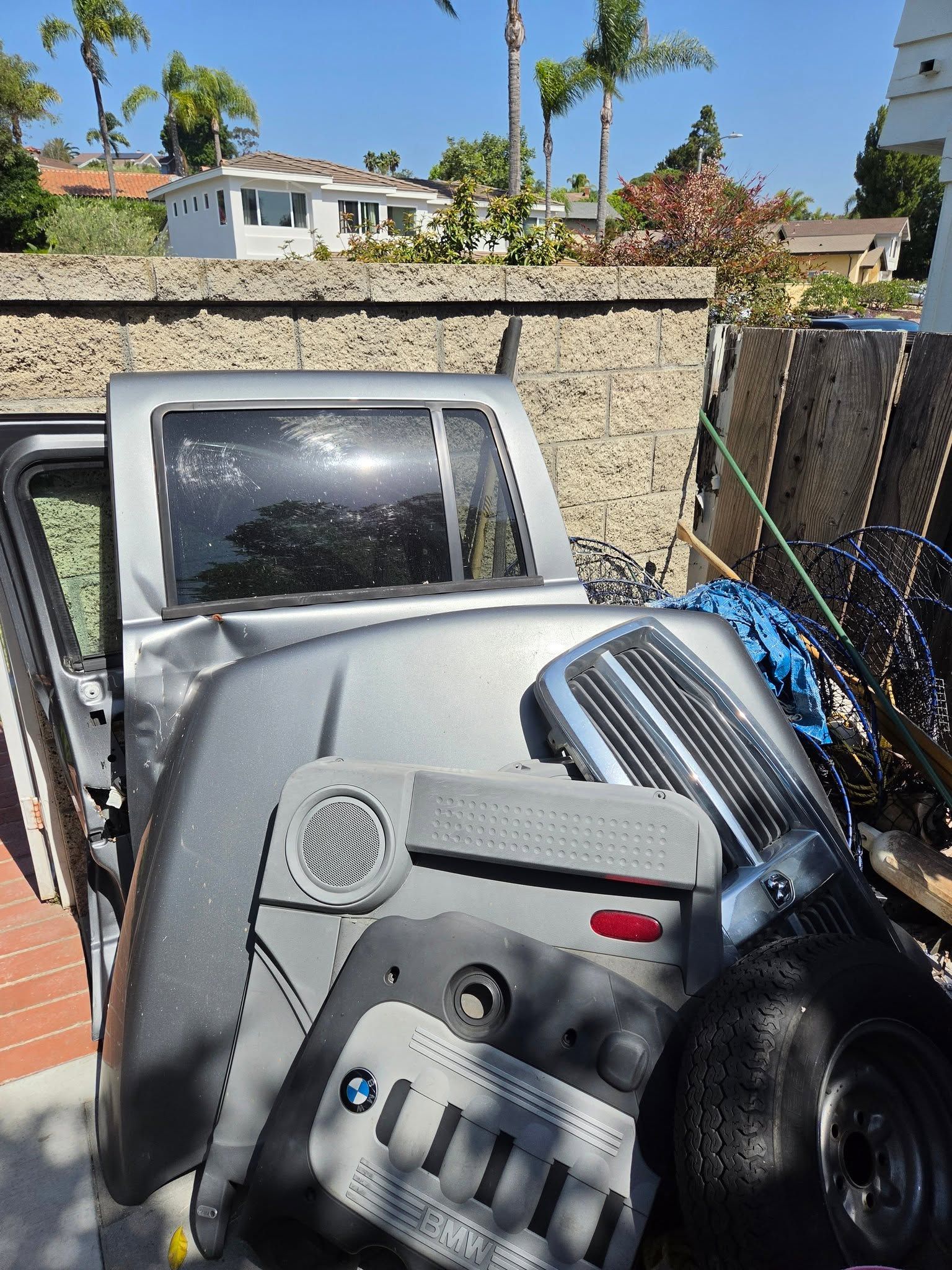 Silver car door interior with dashboard controls and steering wheel, parked beside a stone wall outdoors