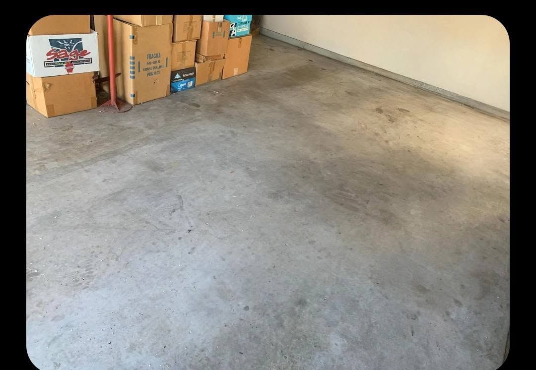 Empty garage corner with cardboard boxes stacked against the wall and a concrete floor.