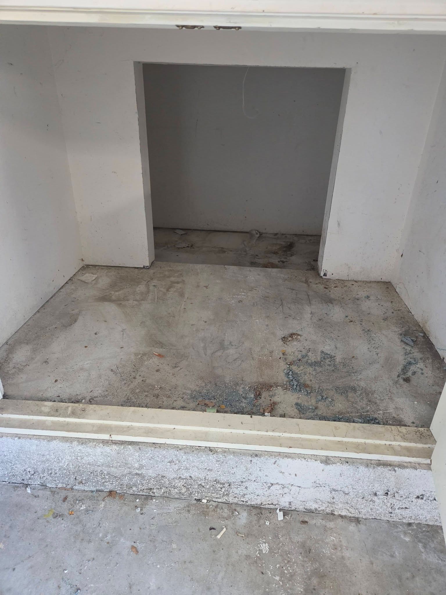 Concrete alcove with a dark recessed opening and rough unfinished floor, viewed from a doorway.