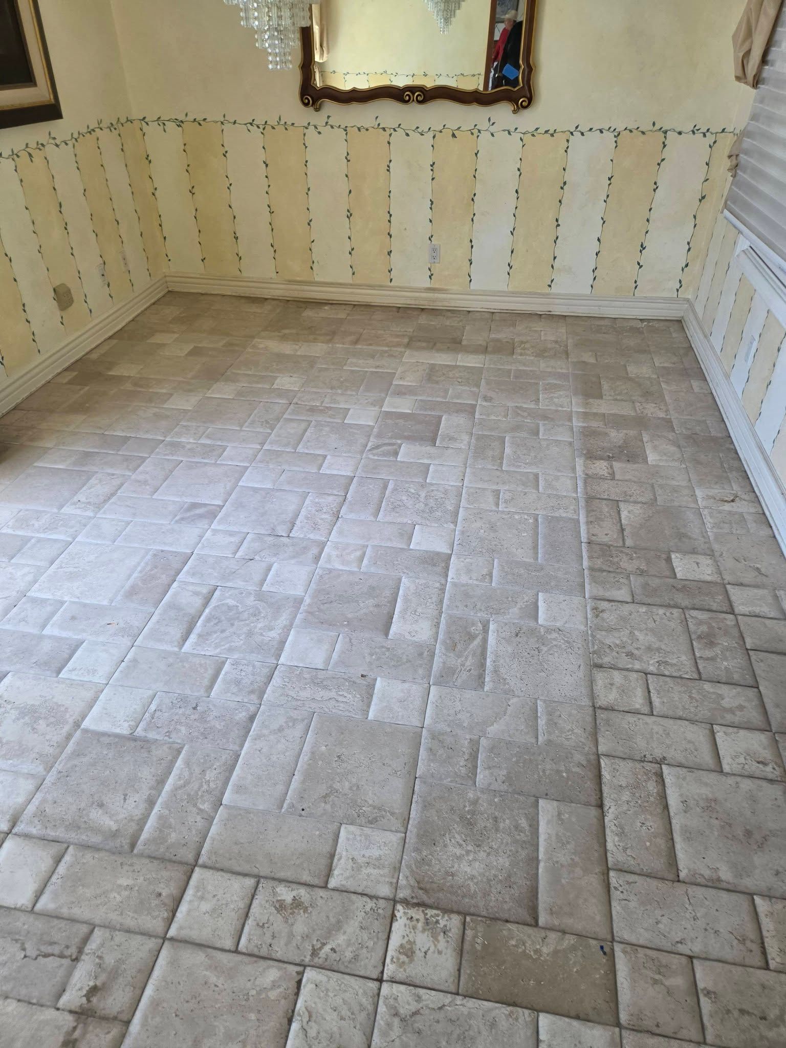 Empty tiled room with patterned floor and striped wallpaper, viewed toward a window