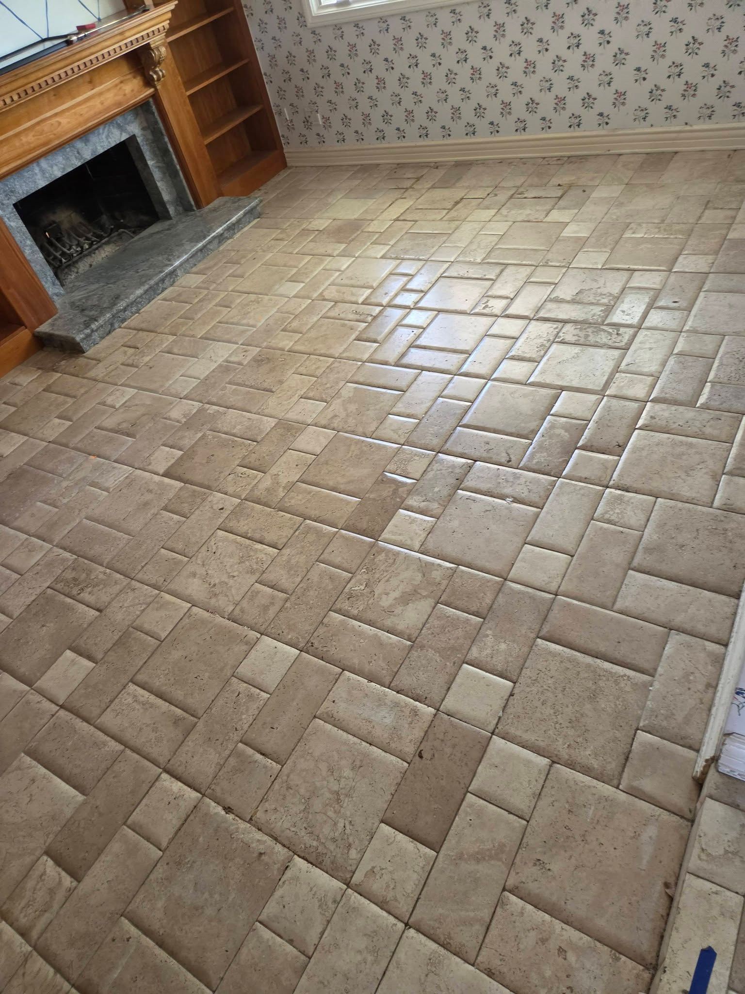 Empty room with tan brick-pattern tile floor and a fireplace on the left.