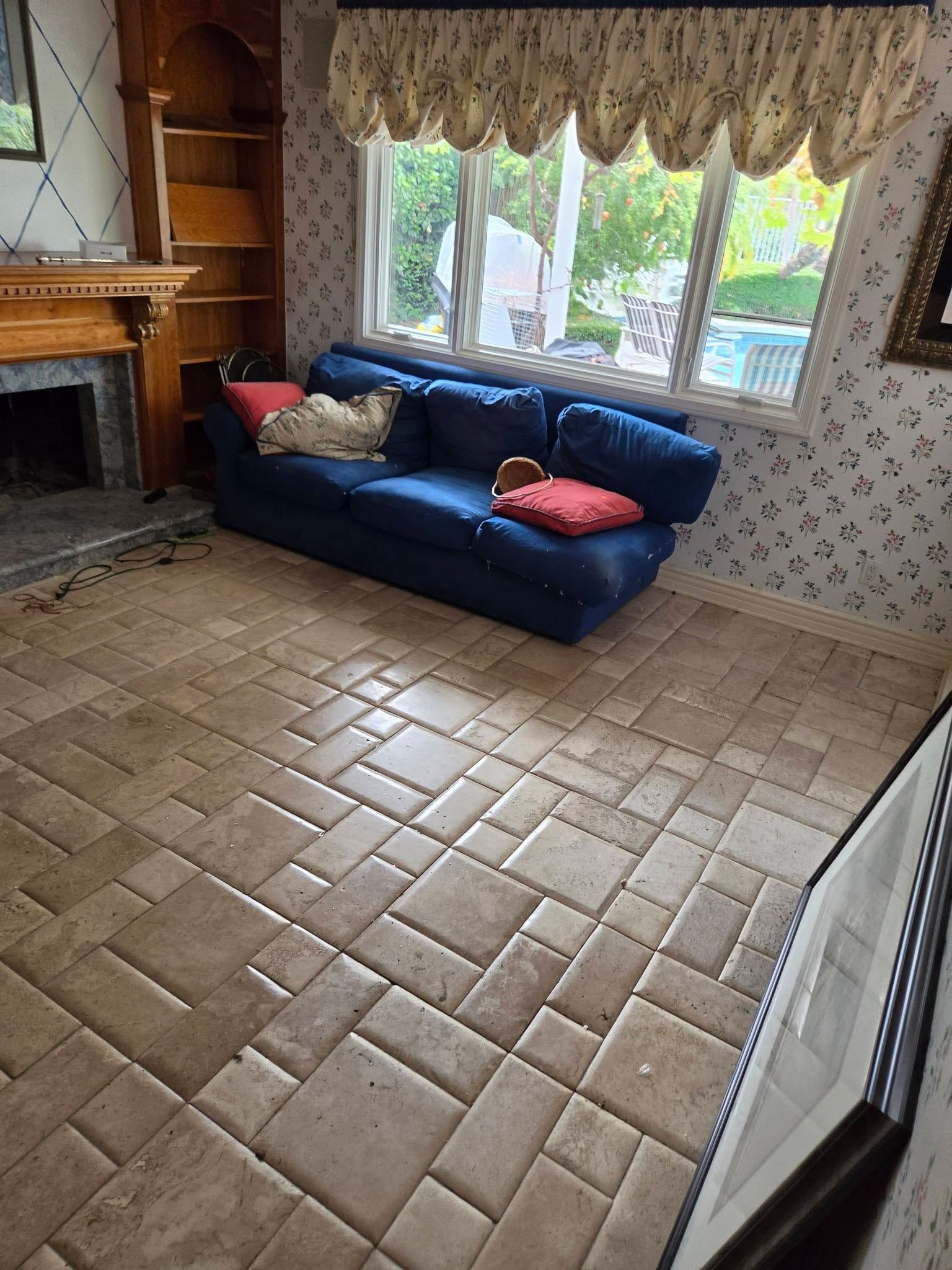 Living room with blue sofa, fireplace, bay window, and tiled floor