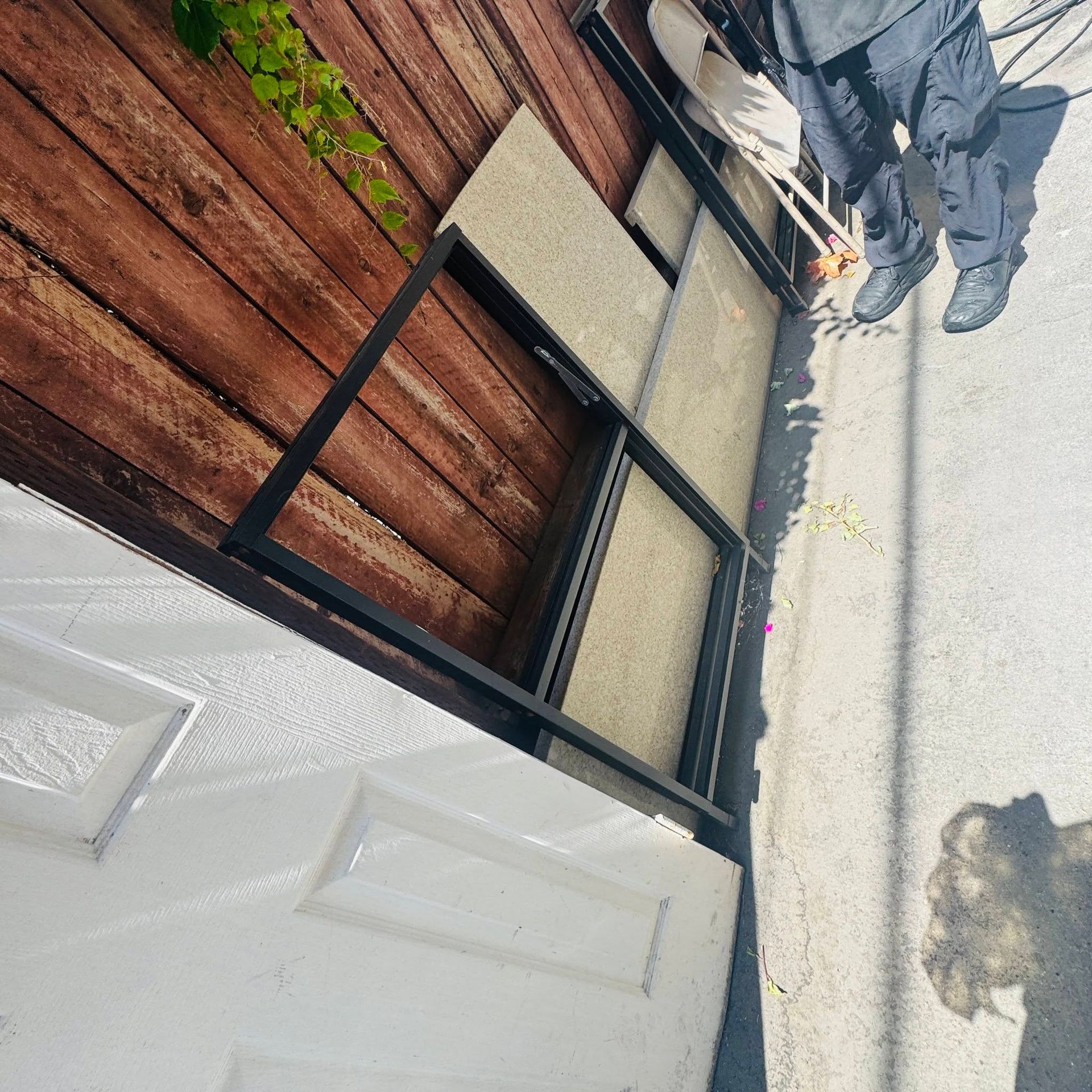 Rotated view of a white door, wooden siding, and black metal railing on a patio.