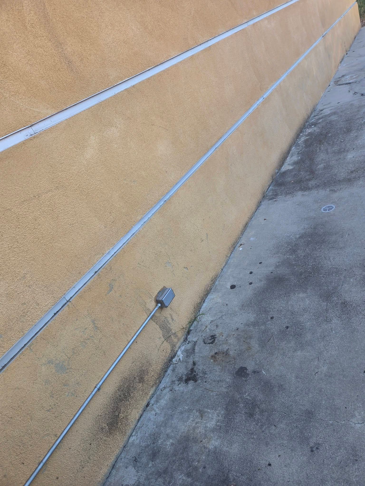 Tan stucco wall with metal rails beside a concrete walkway