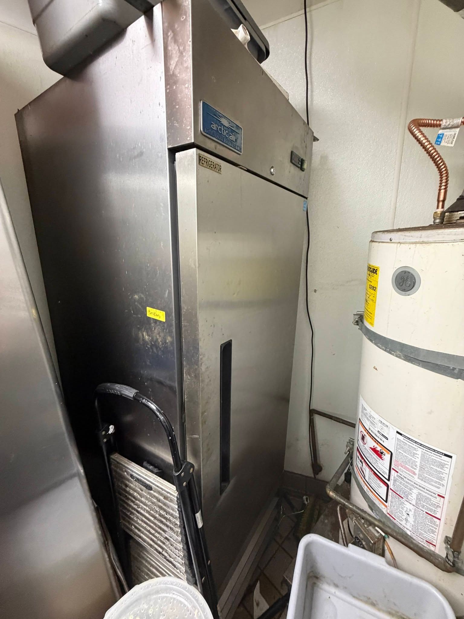 Metal HVAC unit beside a white water heater in a utility room