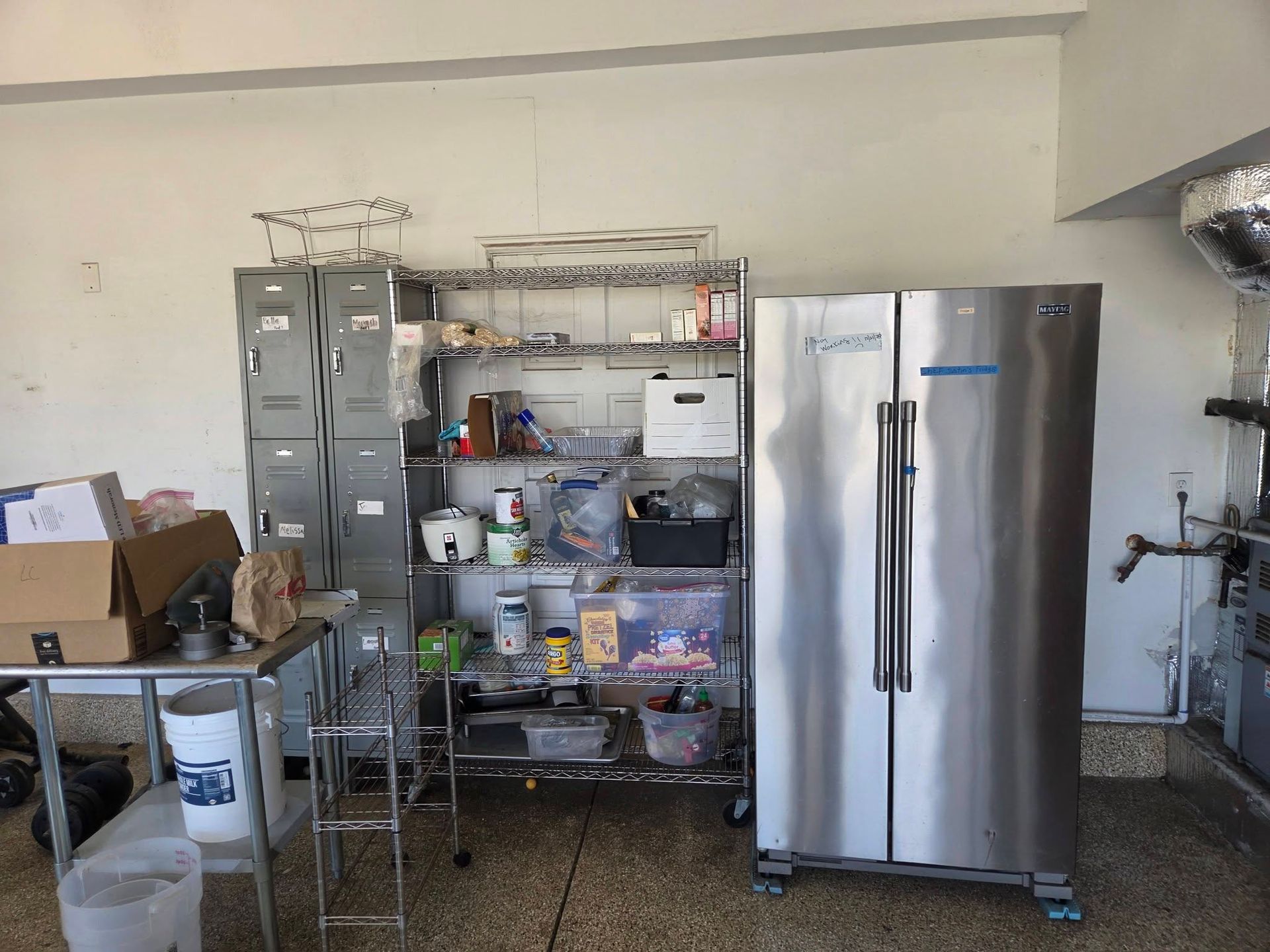 Garage storage area with metal shelves, filing cabinets, and a stainless steel refrigerator.