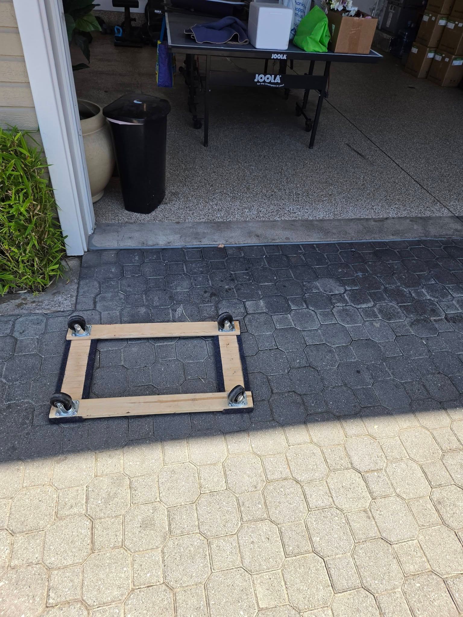 Open garage entrance with a wooden panel lying on the driveway threshold
