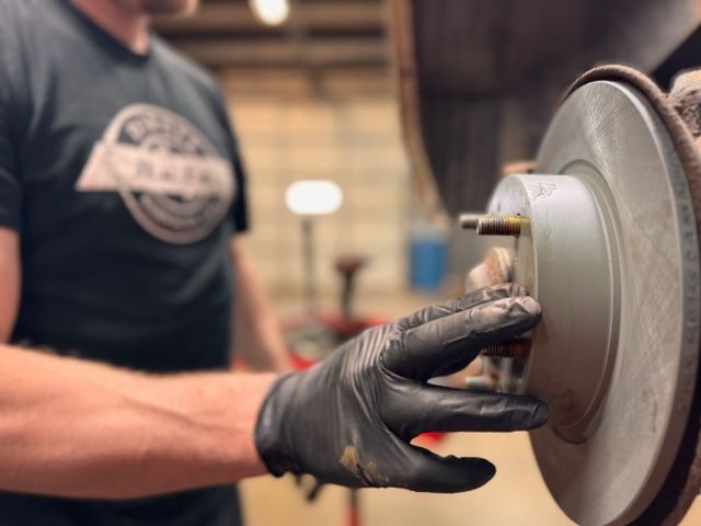 A man wearing black gloves is working on a brake disc
