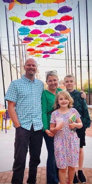 A family is posing for a picture under a bunch of colorful umbrellas.