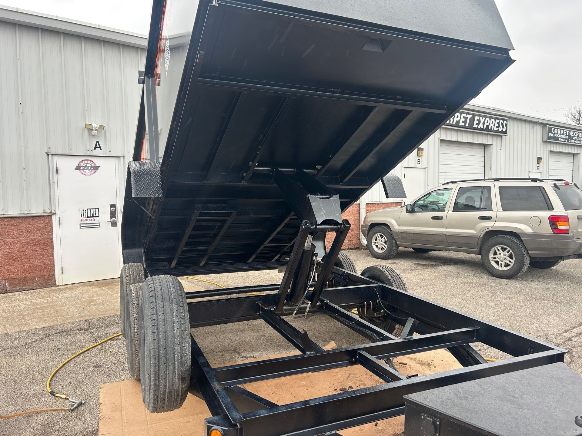 A dump trailer is parked in front of a building.
