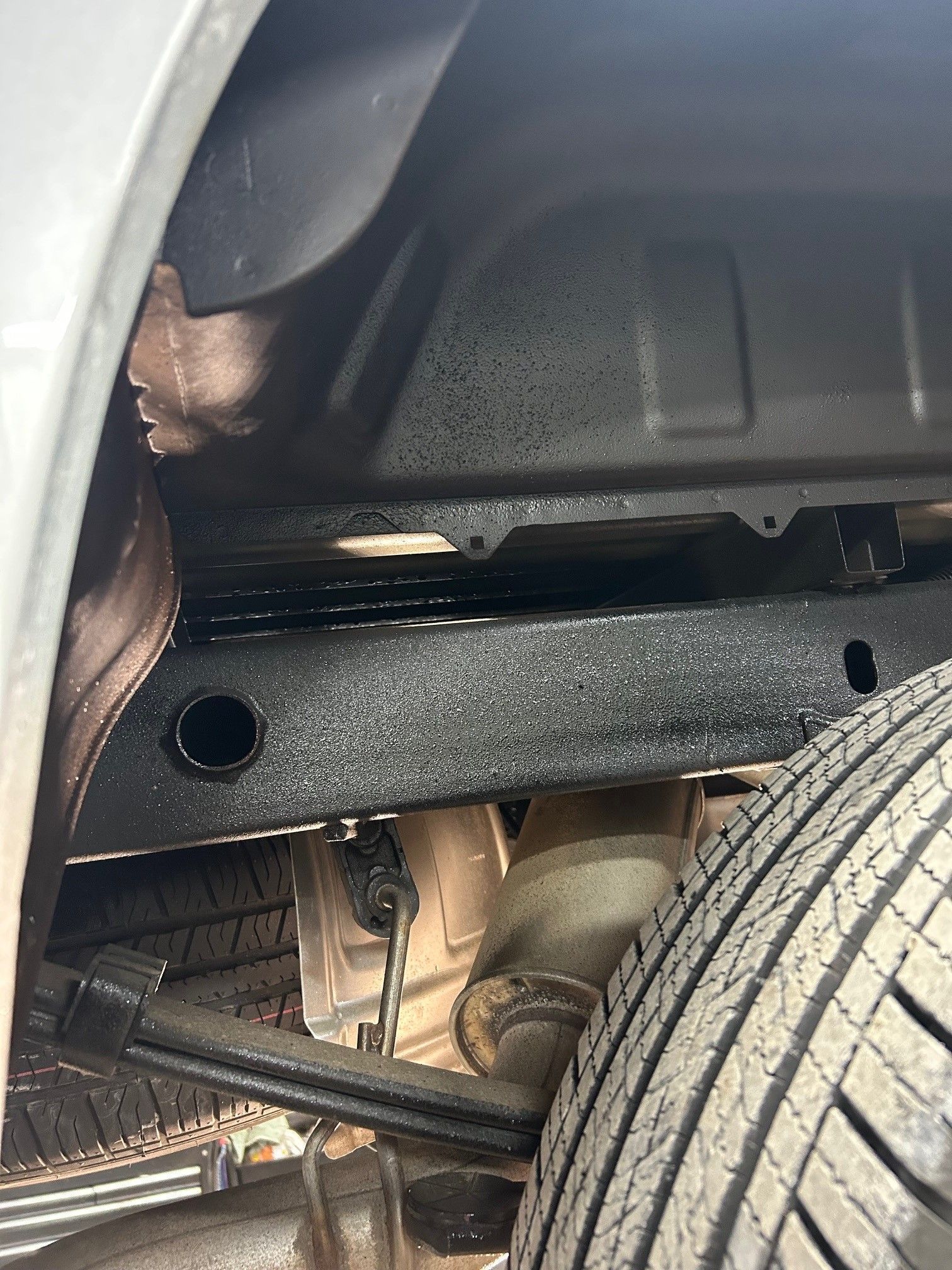 A close up of the underside of a car with a tire.